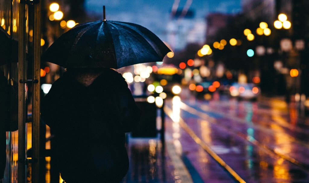 Mann mit Schirm im Regen